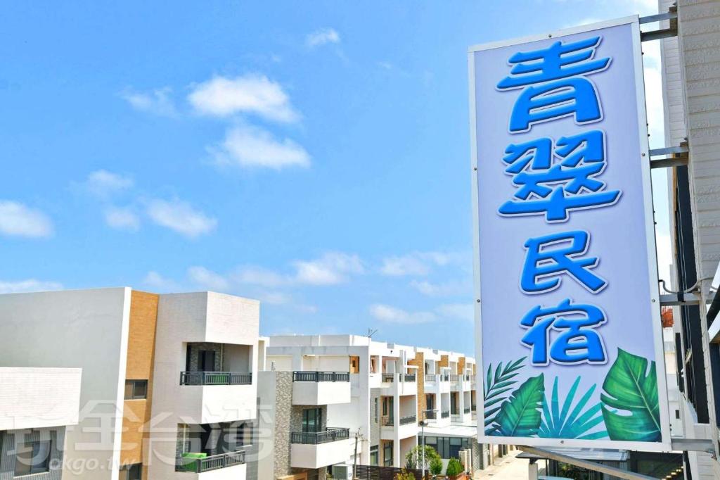 a sign for a hotel in front of some buildings at 青翠民宿 in Magong