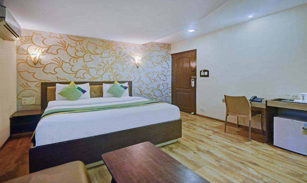 班加羅爾的住宿－Treebo Trend Savoury Sea Shell Residency，酒店客房配有一张床铺、一张桌子和一张书桌。