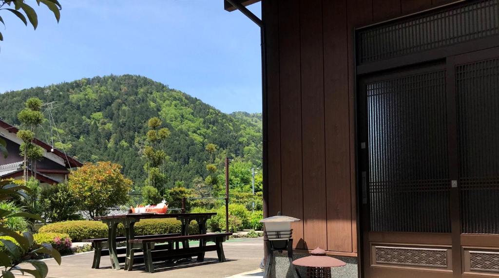 une terrasse avec une table, des bancs et une montagne dans l'établissement Ohara Sensui Surrounded by Beautiful Nature, à Kyoto