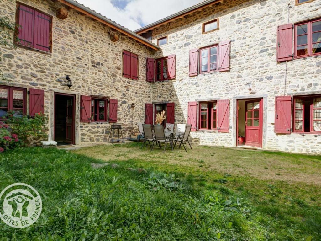 uma casa de pedra com persianas vermelhas e um quintal em Gîte Saint-Just-en-Bas, 4 pièces, 6 personnes - FR-1-496-19 em Saint-Just-en-Bas