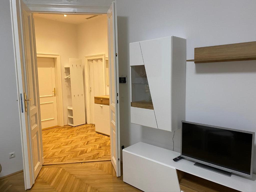 een woonkamer met een tv aan een witte muur bij MQ Appartement in Wenen