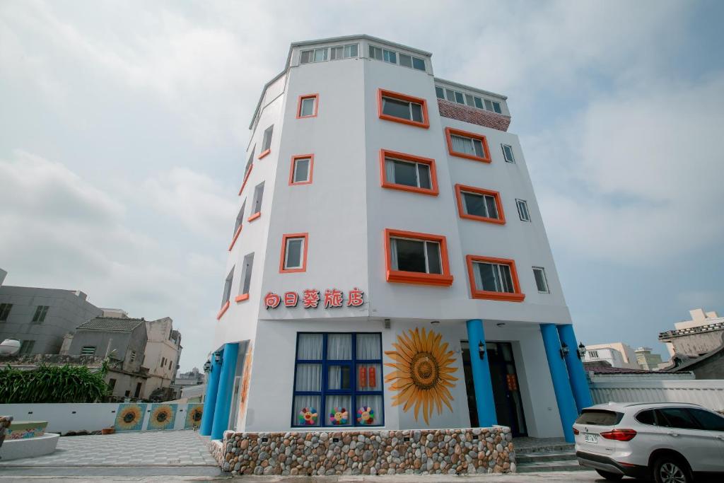 un edificio alto y blanco con un sol. en Sunflower Homestay, en Magong