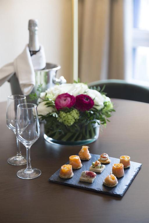 a table with a vase of flowers and a plate of pastries at Warwick Reine Astrid - Lyon in Lyon