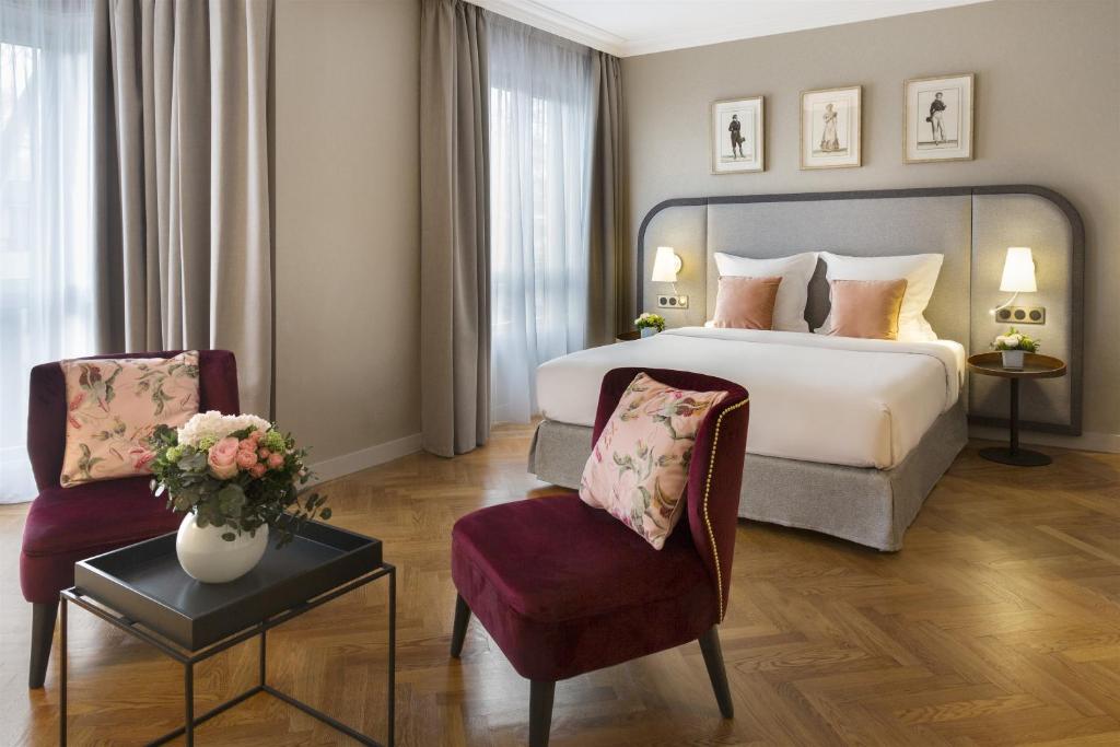 een hotelkamer met een bed en twee stoelen bij Warwick Reine Astrid - Lyon in Lyon