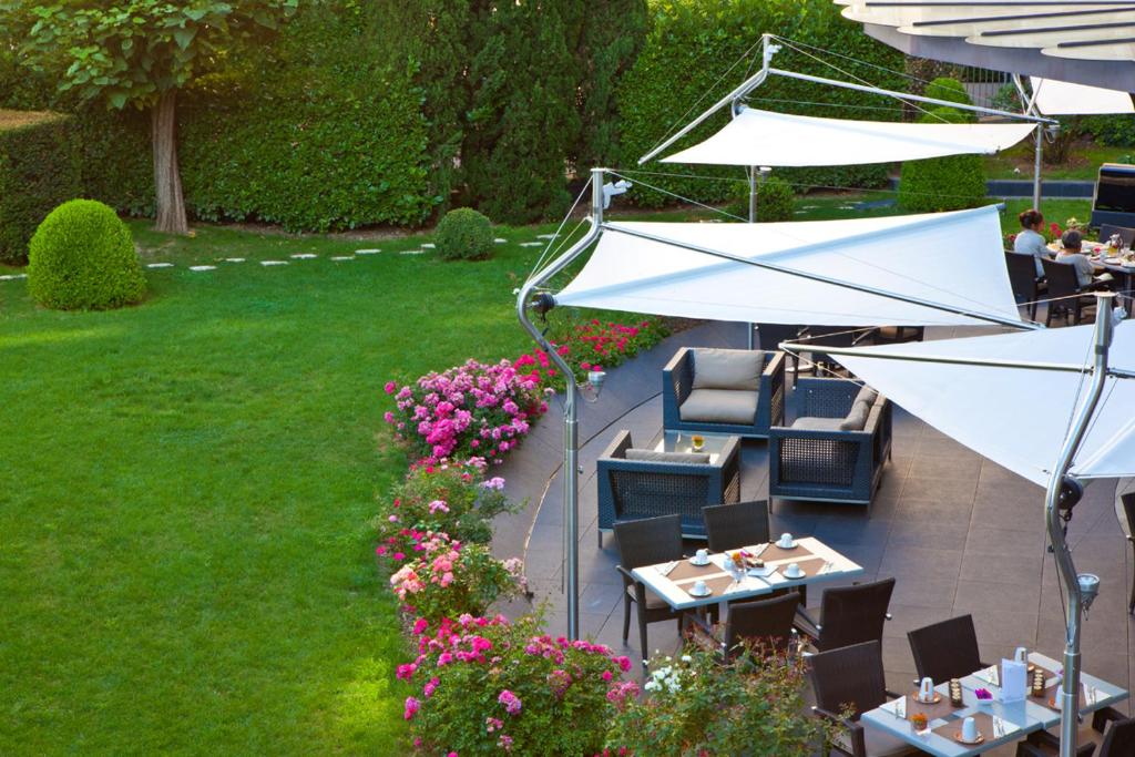 an outdoor patio with tables and chairs and umbrellas at Warwick Reine Astrid - Lyon in Lyon