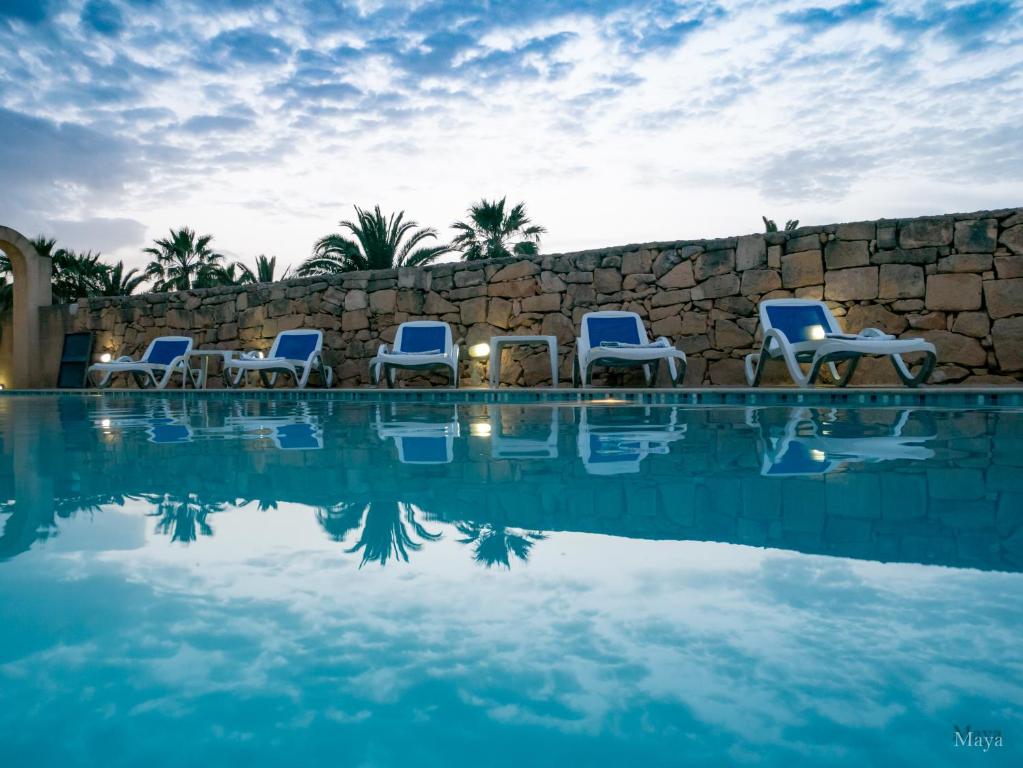 a group of chairs sitting next to a swimming pool at VinDor Villa in Sannat