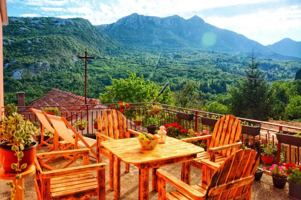 einen Holztisch und Stühle auf einem Balkon mit Bergblick in der Unterkunft Country Lake House Kojicic in Virpazar