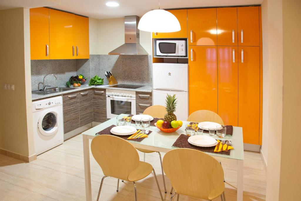 a kitchen with orange cabinets and a table and chairs at Apartamentos Campuebla in Montanejos