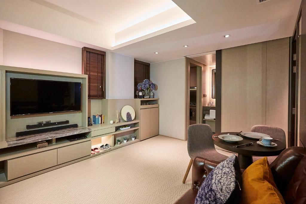 sala de estar con TV, mesa y sillas en Princeton Residence, en Hong Kong