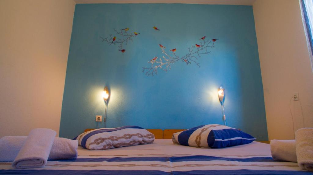 a bed with two pillows and a blue wall at The Sea House Apartments in Vis