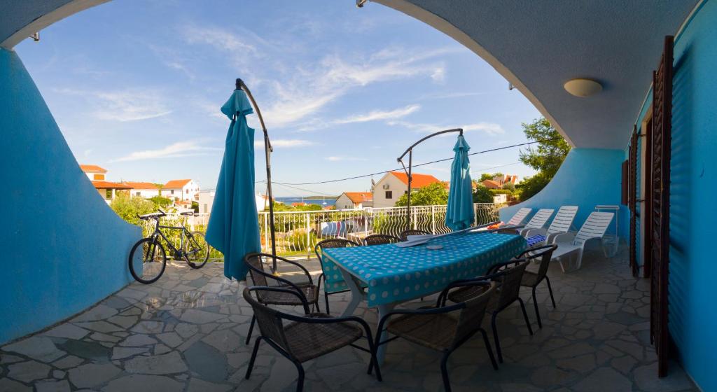 a patio with a blue table and chairs and umbrellas at The Sea House Apartments in Vis