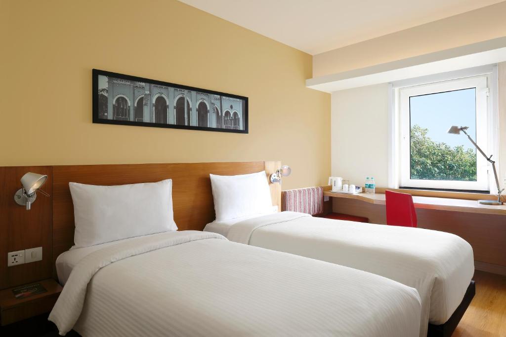 two beds in a hotel room with a window at ibis Pune Viman Nagar - An Accor Brand in Pune