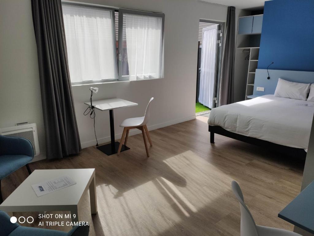 a bedroom with a bed and a desk and a bed and a table at Atao Residence- Rennes Sud in Vern-sur-Seiche