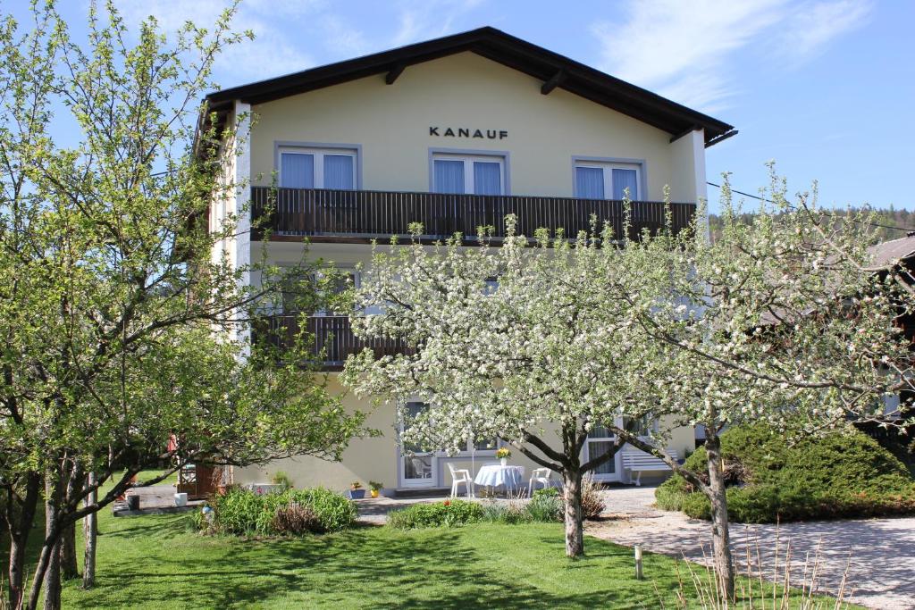 eine Villa mit einem Garten und Bäumen davor in der Unterkunft Appartements Kanauf in Krumpendorf am Wörthersee