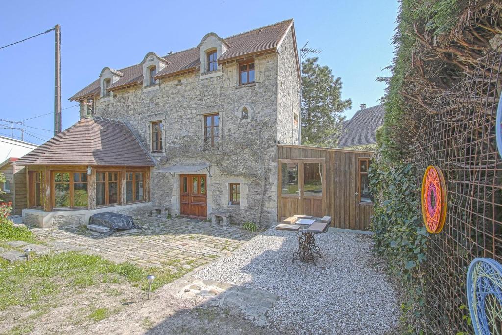 une grande maison en pierre avec une clôture devant elle dans l'établissement LE TIVOLI 1853, à Grandcamp-Maisy