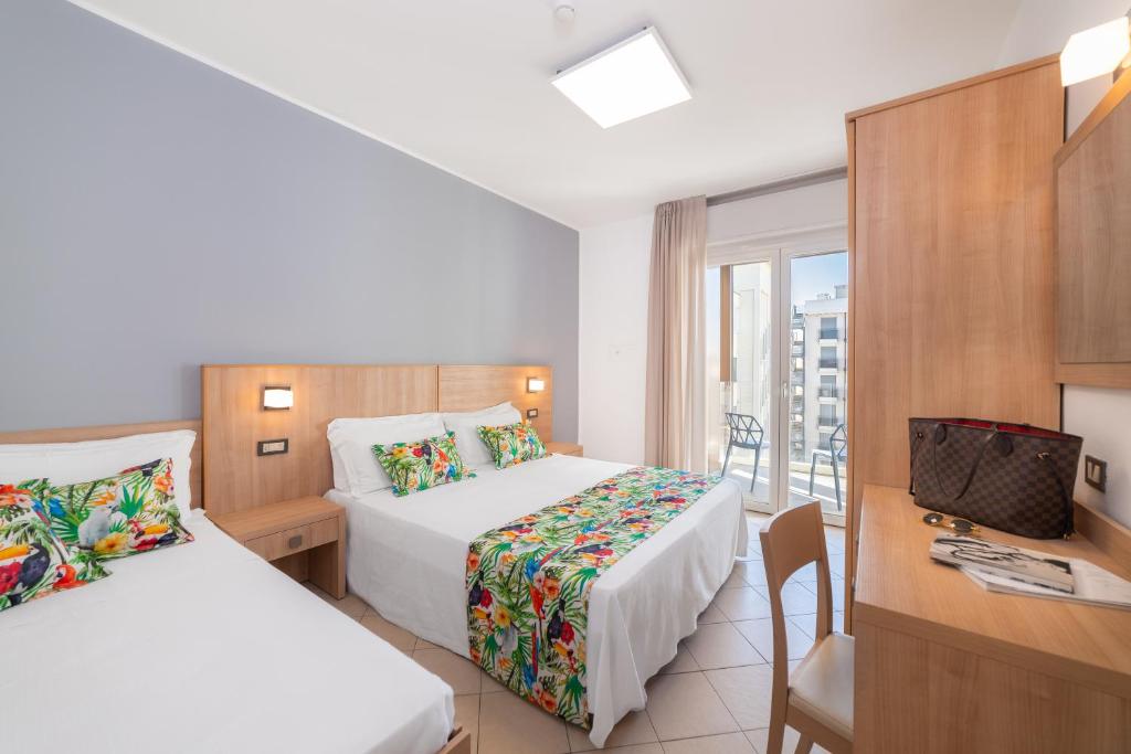 a hotel room with two beds and a desk at Amalfi smart Rooms & Apartments - Ideale per Ragazzi in Riccione