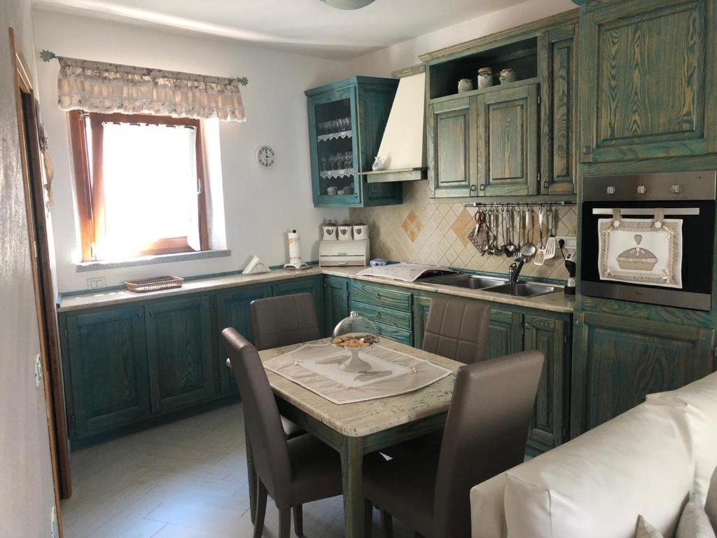 a kitchen with green cabinets and a table with chairs at Casa Azzurra in Santa Teresa Gallura