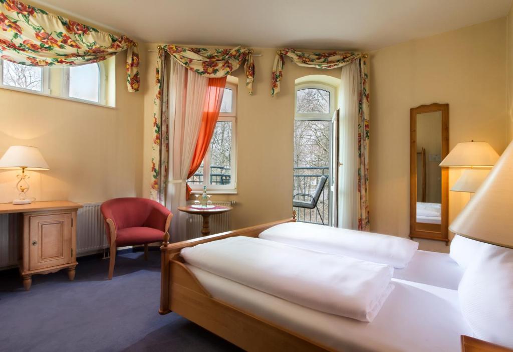 een slaapkamer met een bed, een bureau en ramen bij Hotel Schloss Schweinsburg in Neukirchen-Pleiße