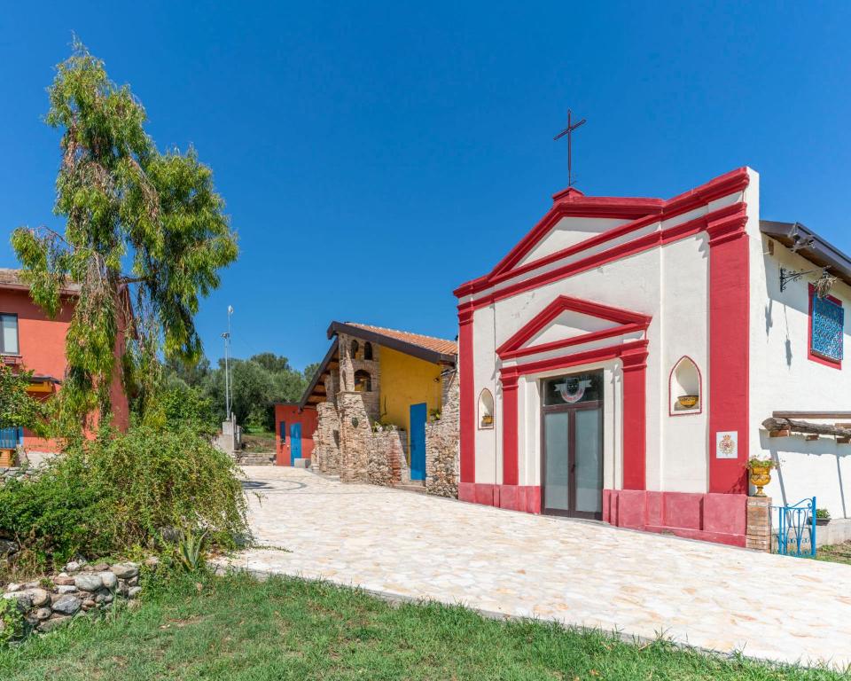 eine kleine rot-weiße Kirche mit einem Kreuz auf dem Dach in der Unterkunft Tenuta Le Tre Querce in Seminara