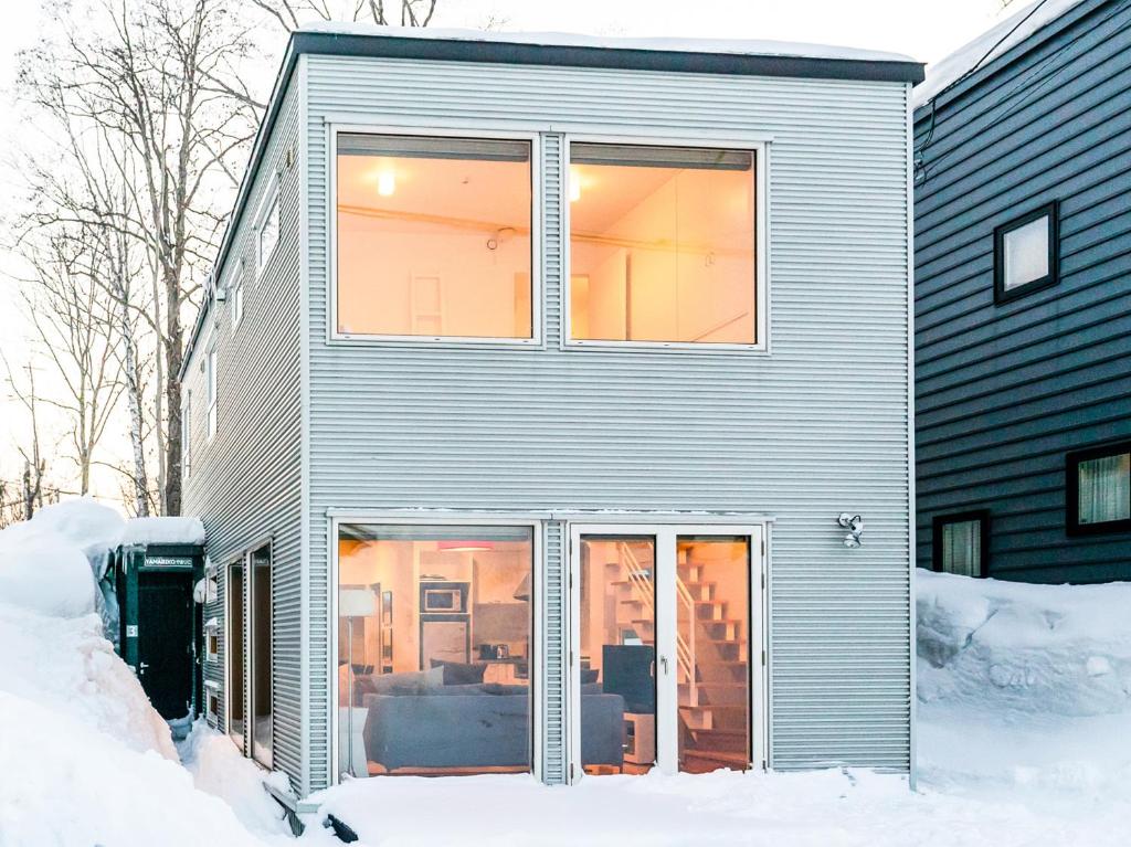 a house with sliding glass doors in the snow at Yamabiko Chalet in Niseko