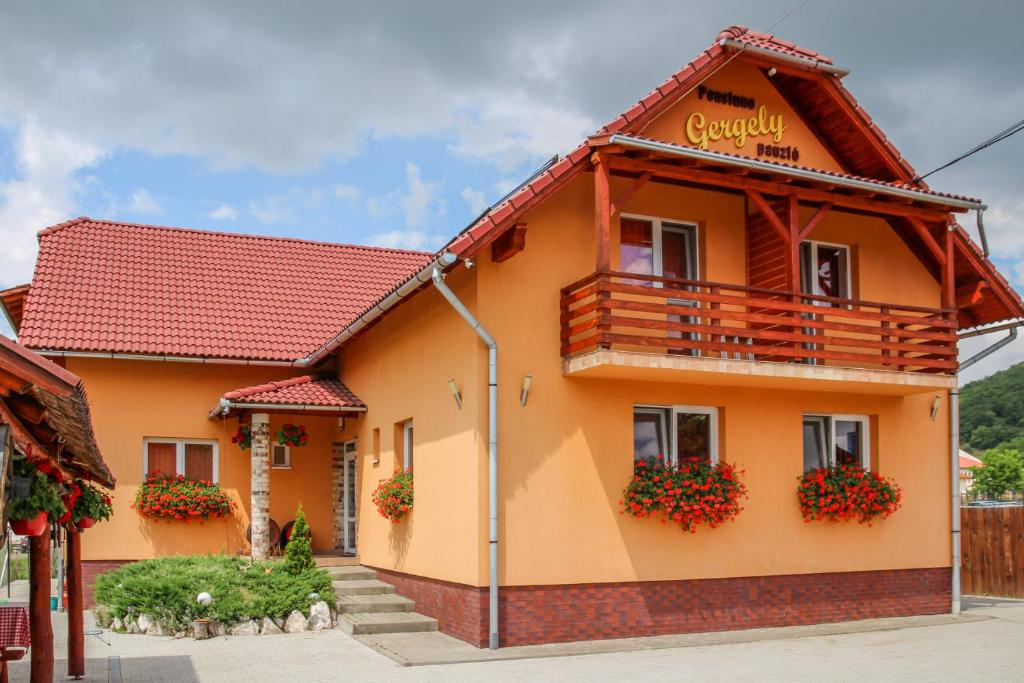 a house with a balcony and flowers on it at Apartamente Gergely Apartmanok in Praid