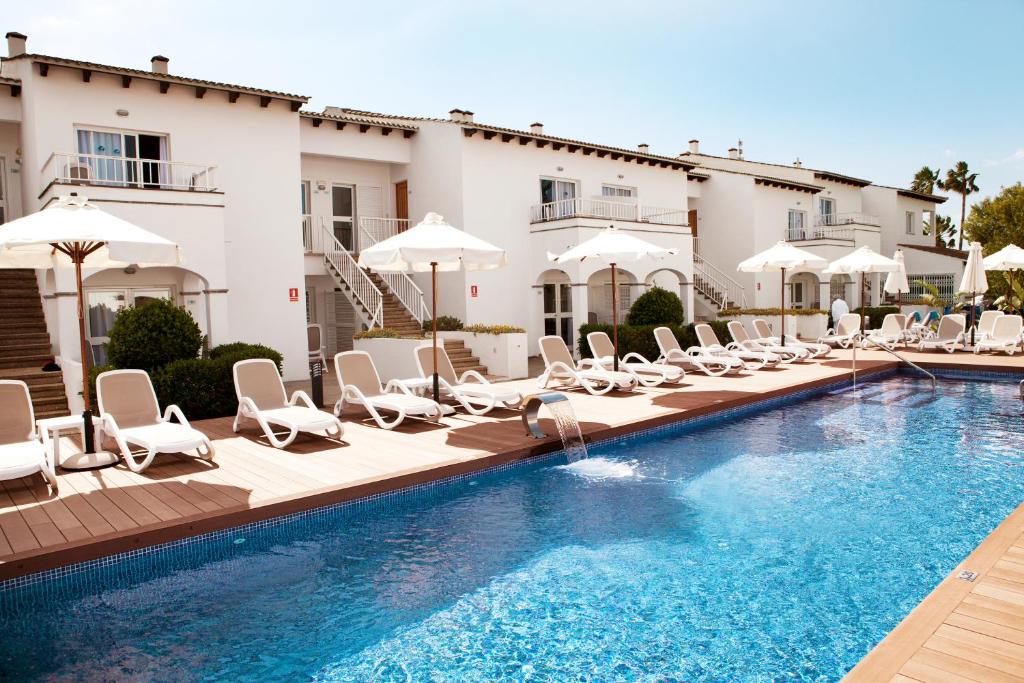 a swimming pool with lounge chairs and a hotel at Serenity Apartments in Port d'Alcudia