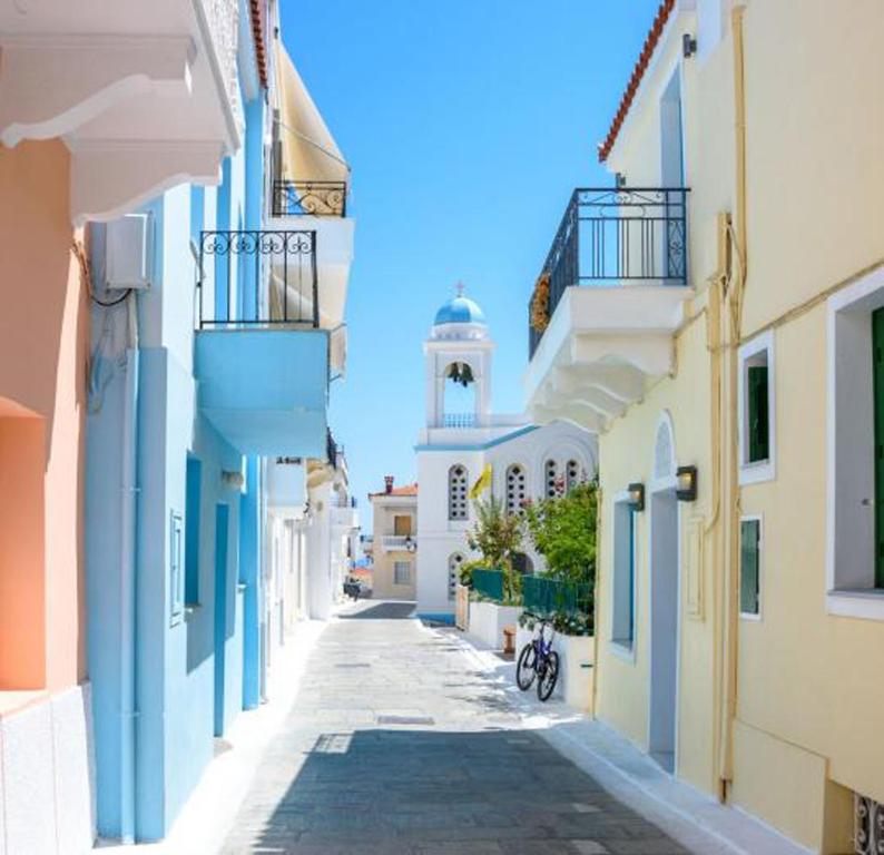 a street in a town with a lighthouse in the distance at Castel Abaso Boutique Apartments by Explore Andros in Andros