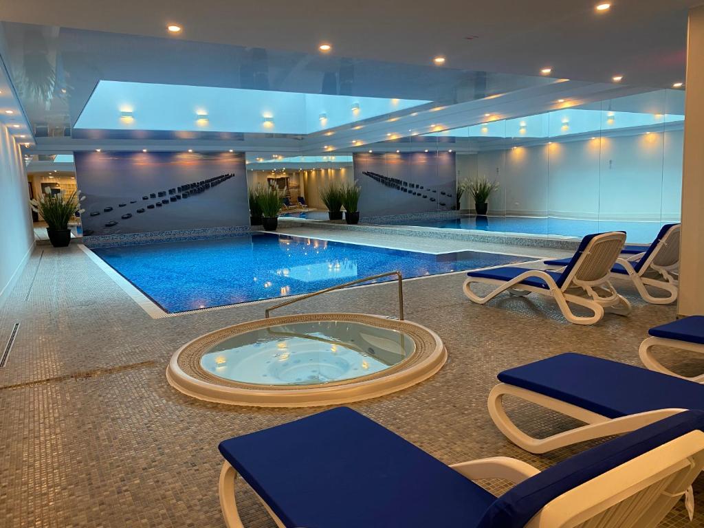 a large swimming pool with chairs and a hot tub at Waterlane by Vivendi Properties in Gdańsk