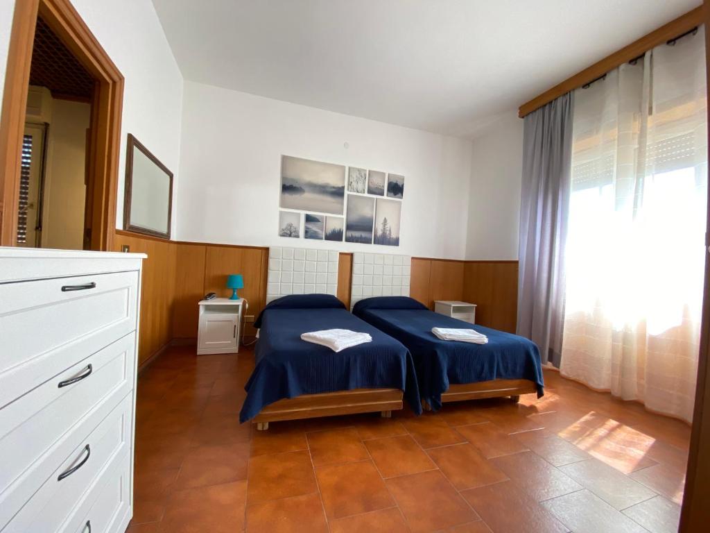 Schlafzimmer mit einem Bett mit blauer Bettwäsche und einem Fenster in der Unterkunft Residence Hotel Valery in Monterotondo