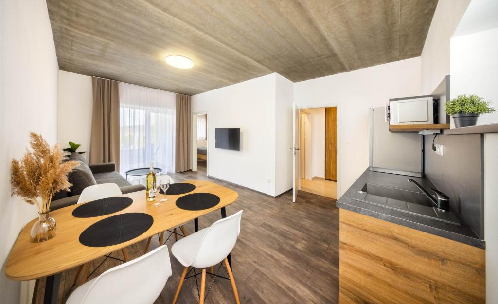 a living room with a wooden table and white chairs at Apartmány Panelka Costa Plana Lipno in Černá v Pošumaví