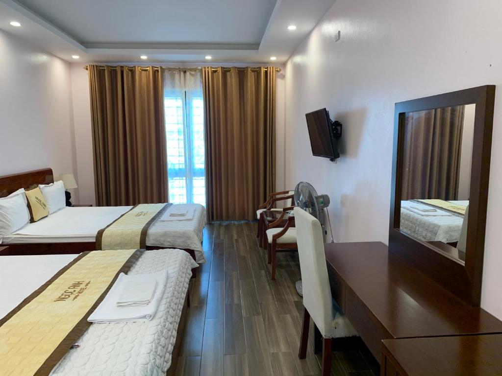 a hotel room with two beds and a table and a television at Hotel Ngoc Anh - Van Don in Quang Ninh