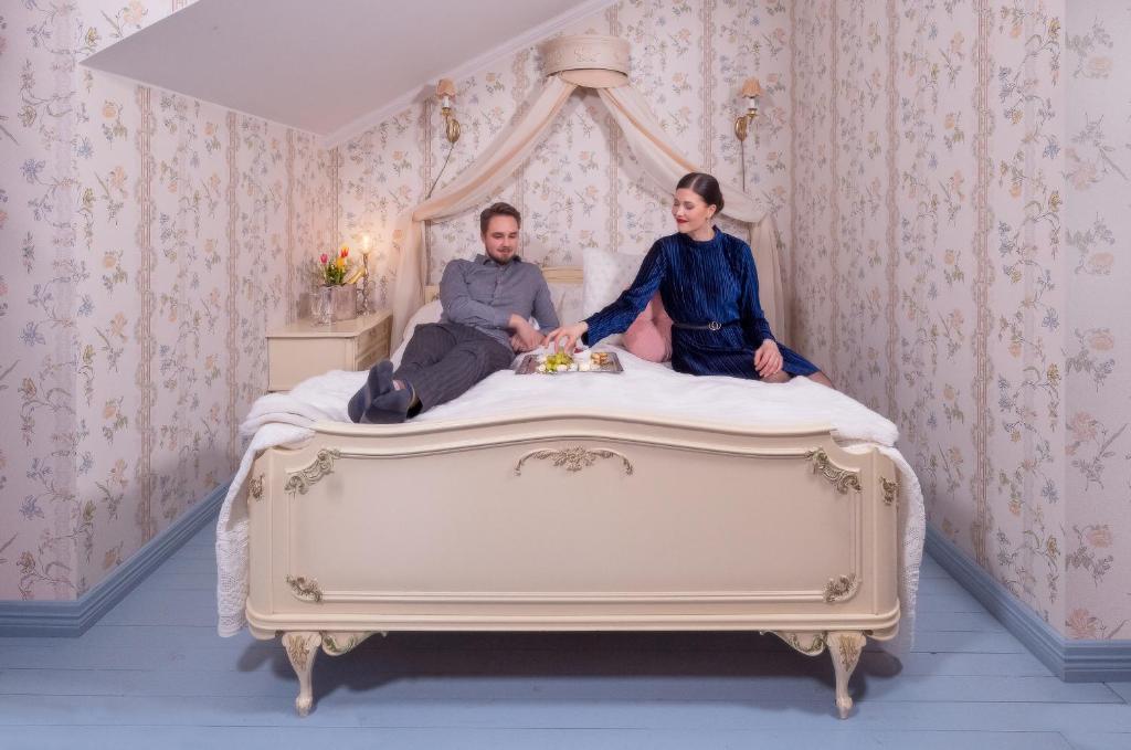 un hombre y una mujer sentados en una cama en Taulun Kartano, en Kankainen