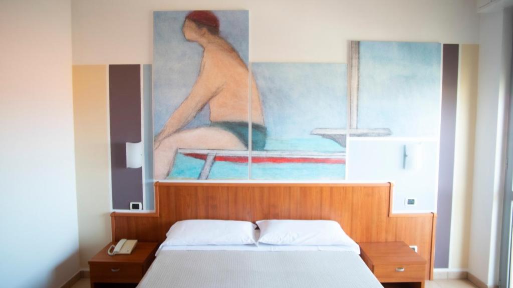 a bedroom with a bed with a painting on the wall at Hotel Royal in Giulianova