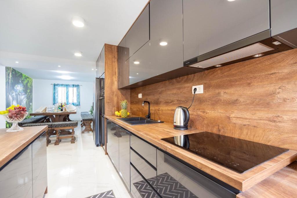 a kitchen with a sink and wooden wall at VILLA STARS HILL WITH HEATING POOL and JACUZZI - MAKARSKA in Slivno