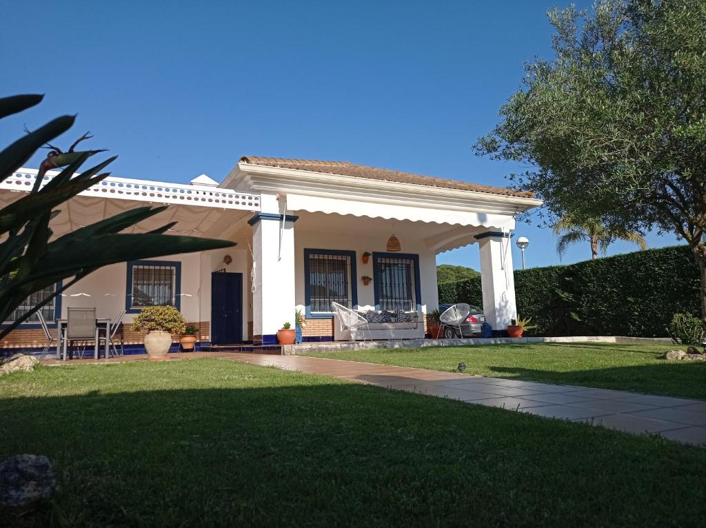 uma casa branca com um alpendre e um relvado em ONUBA golf, sea & sun em El Portil