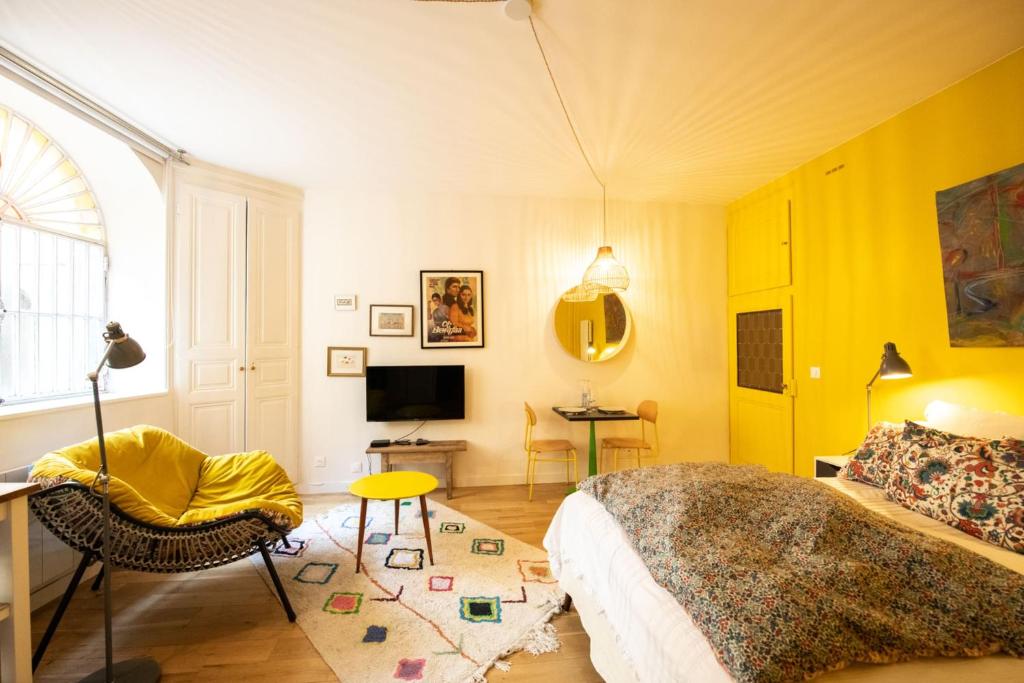 - une chambre avec des murs jaunes, un lit et une télévision dans l'établissement Le Studio Gab's - Coup de coeur déco tout confort, à Caluire-et-Cuire