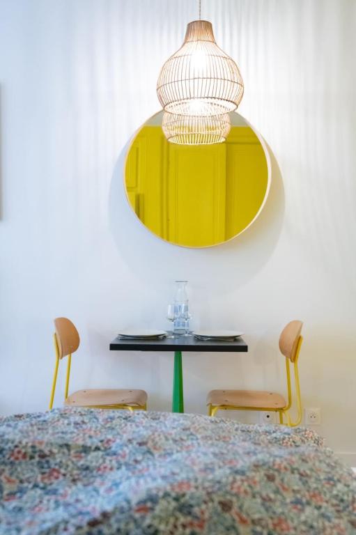 a bedroom with a table with two chairs and a yellow lamp at Le Studio Gab&#39;s - Coup de coeur déco tout confort in Caluire-et-Cuire