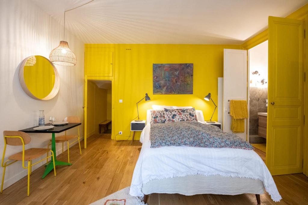 a bedroom with a bed and a yellow wall at Le Studio Gab&#39;s - Coup de coeur déco tout confort in Caluire-et-Cuire