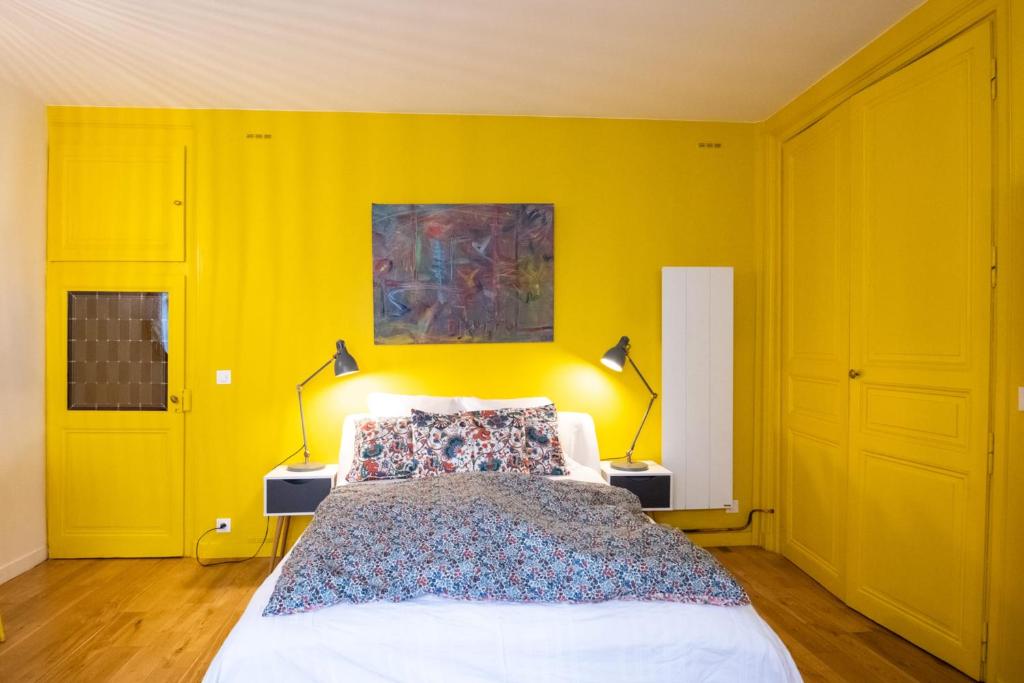 a bedroom with yellow walls and a bed with two lamps at Le Studio Gab&#39;s - Coup de coeur déco tout confort in Caluire-et-Cuire