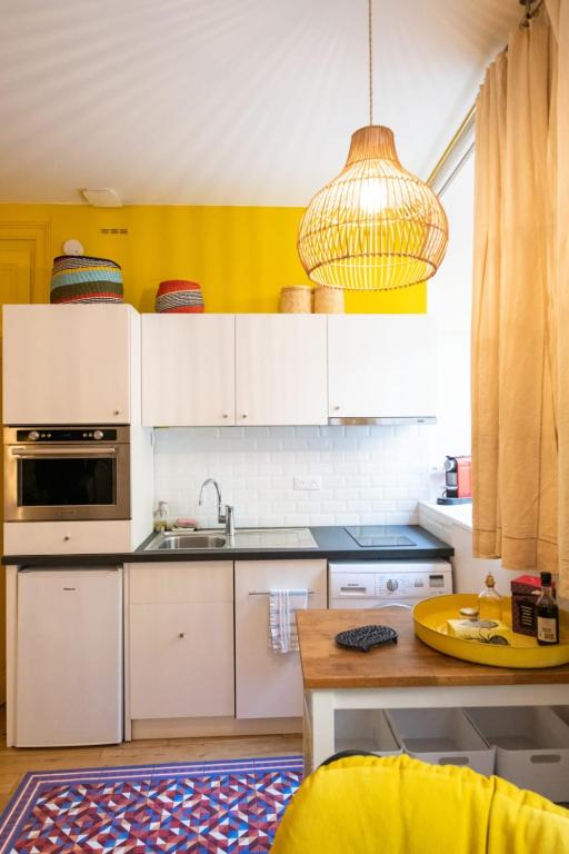 a kitchen with white cabinets and a yellow wall at Le Studio Gab&#39;s - Coup de coeur déco tout confort in Caluire-et-Cuire