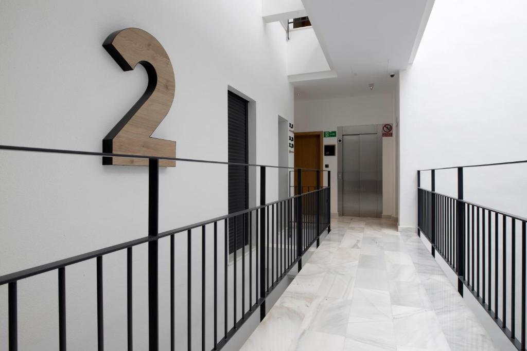 a hallway with white walls and a staircase with black railings at Goodnight Cádiz Apartments in Cádiz