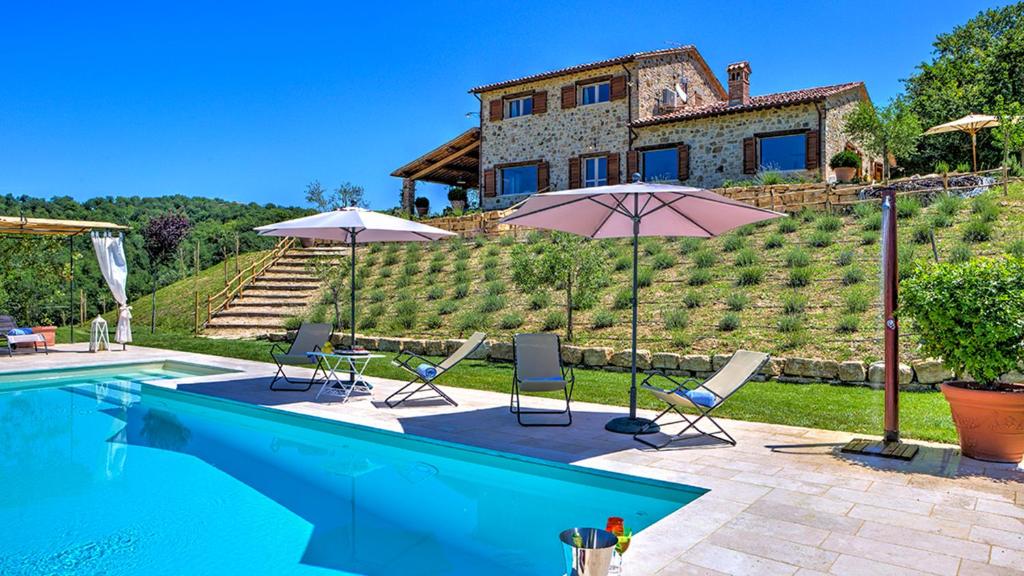una casa con piscina con sedie e ombrelloni di CASALE DEI GELSOMINI 8, Emma Villas a Todi