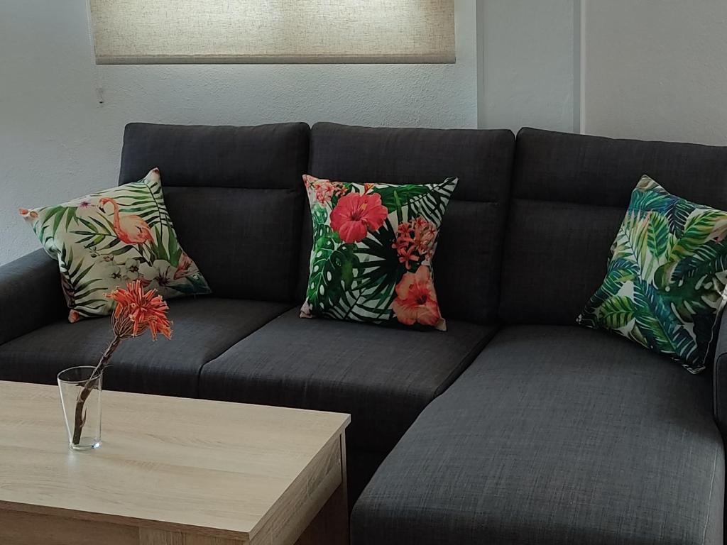 a black couch with pillows and a coffee table at Apartamentos Bolonia - M a n u e l a in Bolonia
