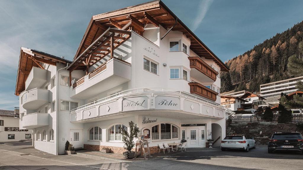 a large white building with a wooden roof at Hotel Föhre in Ischgl