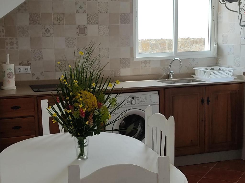 a kitchen with a table and a vase of flowers at Apartamentos Bolonia - M a n u e l a in Bolonia