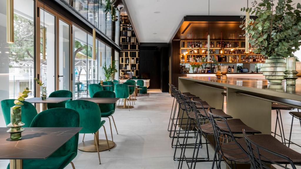 um restaurante com cadeiras verdes e um bar em We Me Suite Hotel em Riccione