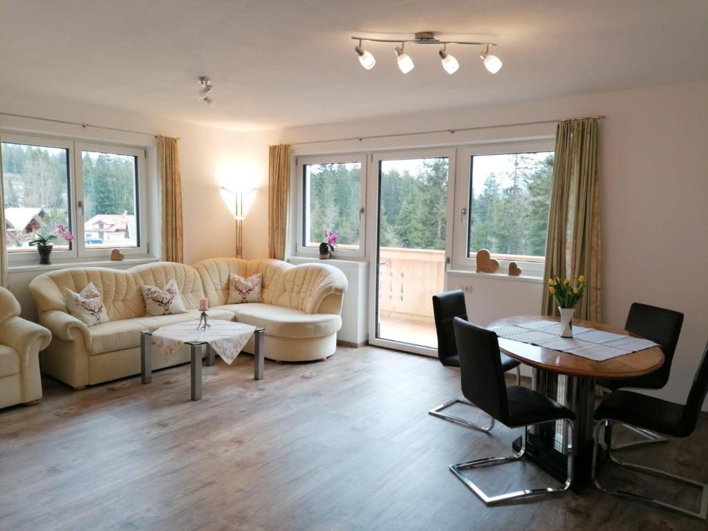 - un salon avec des canapés, des tables et des fenêtres dans l'établissement Appartement Kaiserplatzl, à Scheffau am Wilden Kaiser