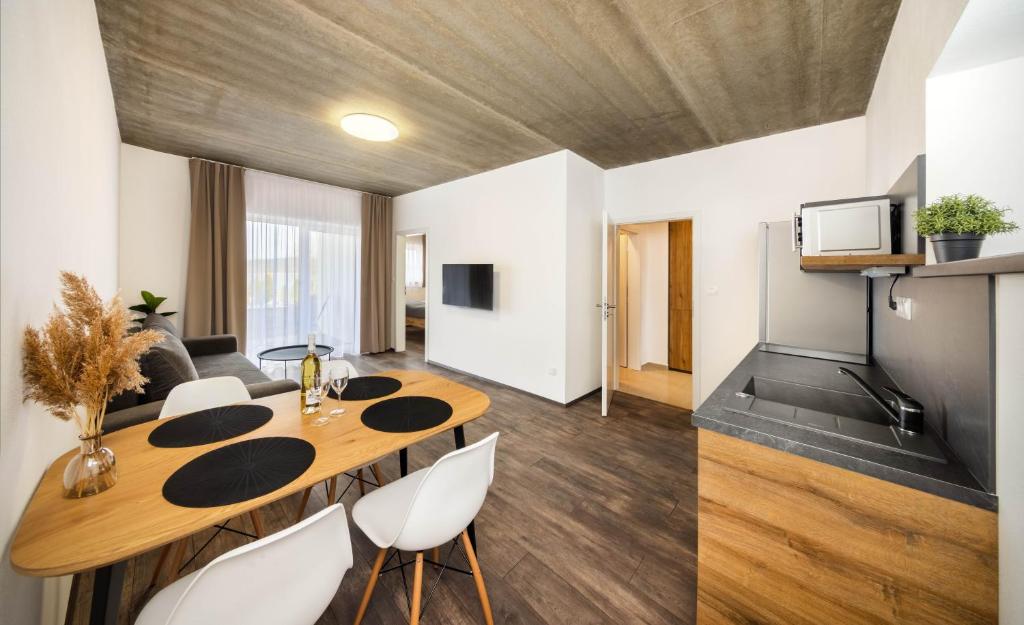 a living room with a wooden table and white chairs at Apartmány Panelka Costa Plana Lipno in Černá v Pošumaví
