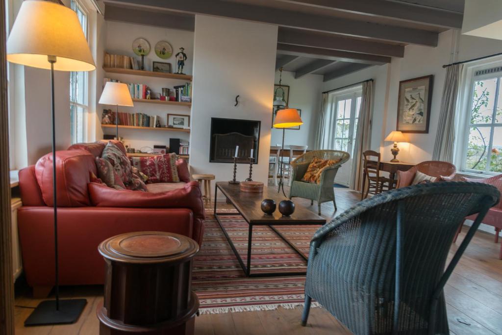 ein Wohnzimmer mit einem roten Sofa und einem TV in der Unterkunft Hello Zeeland - Vakantiehuis Klakbaan 4 in IJzendijke