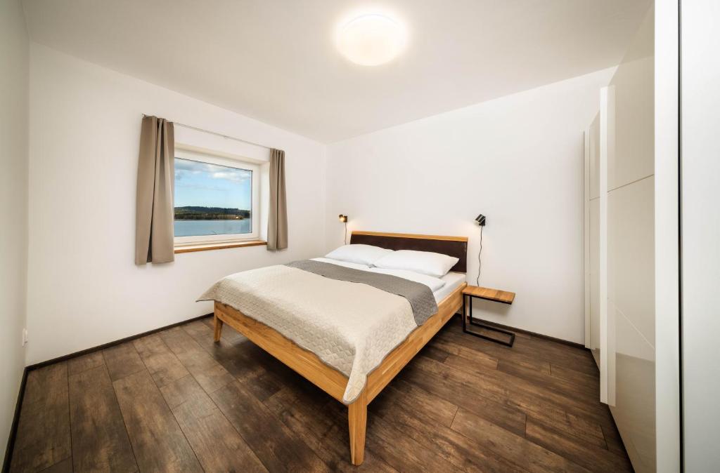 a bedroom with a bed and a window at Apartmány Panelka Costa Plana Lipno in Černá v Pošumaví